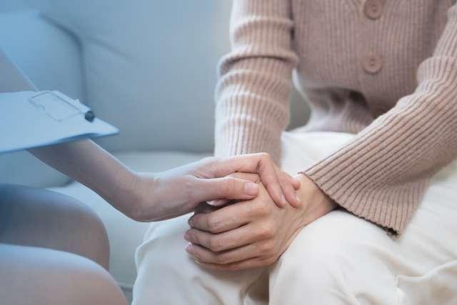 a person's hand on another person's hand in a gesture of comfort